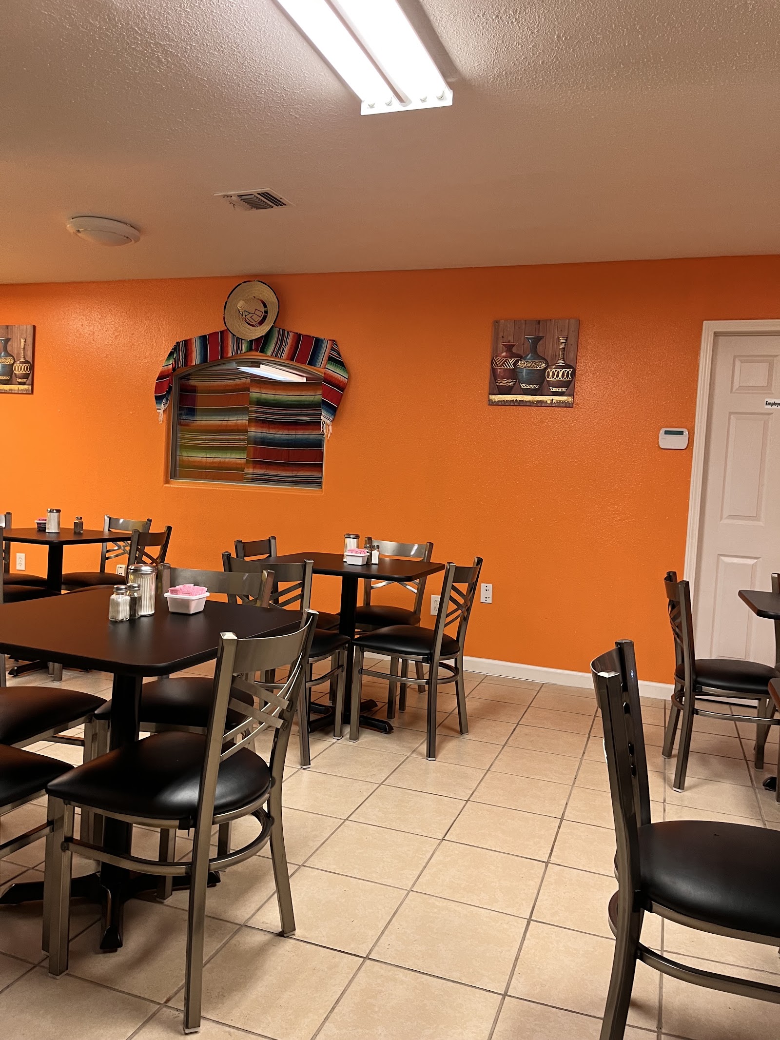 Cozy dining room at La Pasadita Cocina Mexicana with colorful orange walls and Mexican decor