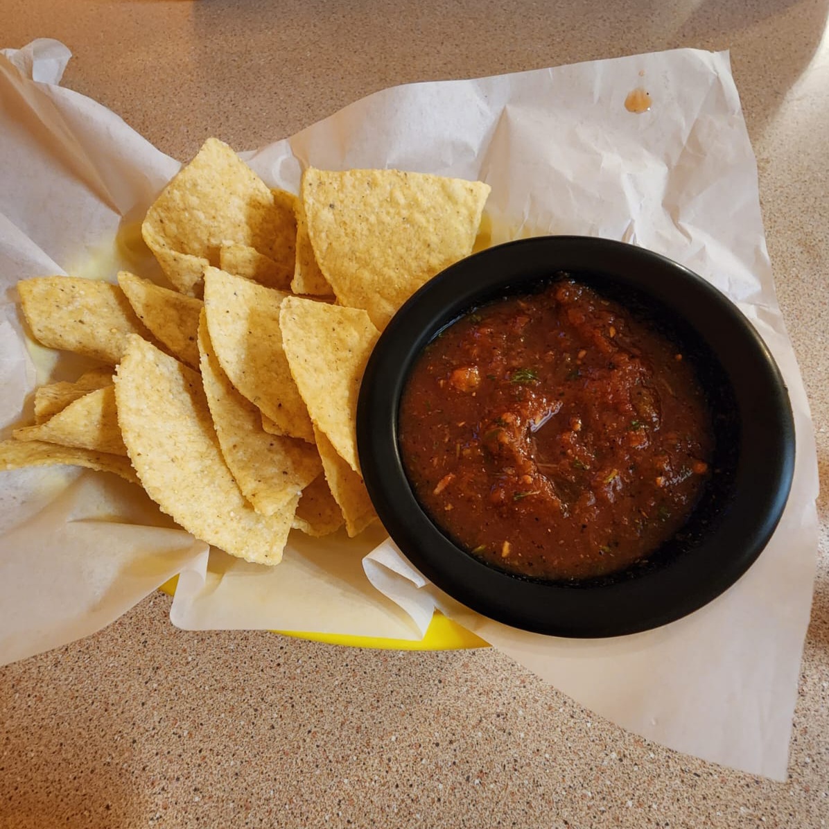 Basket of fresh tortilla chips with homemade red salsa