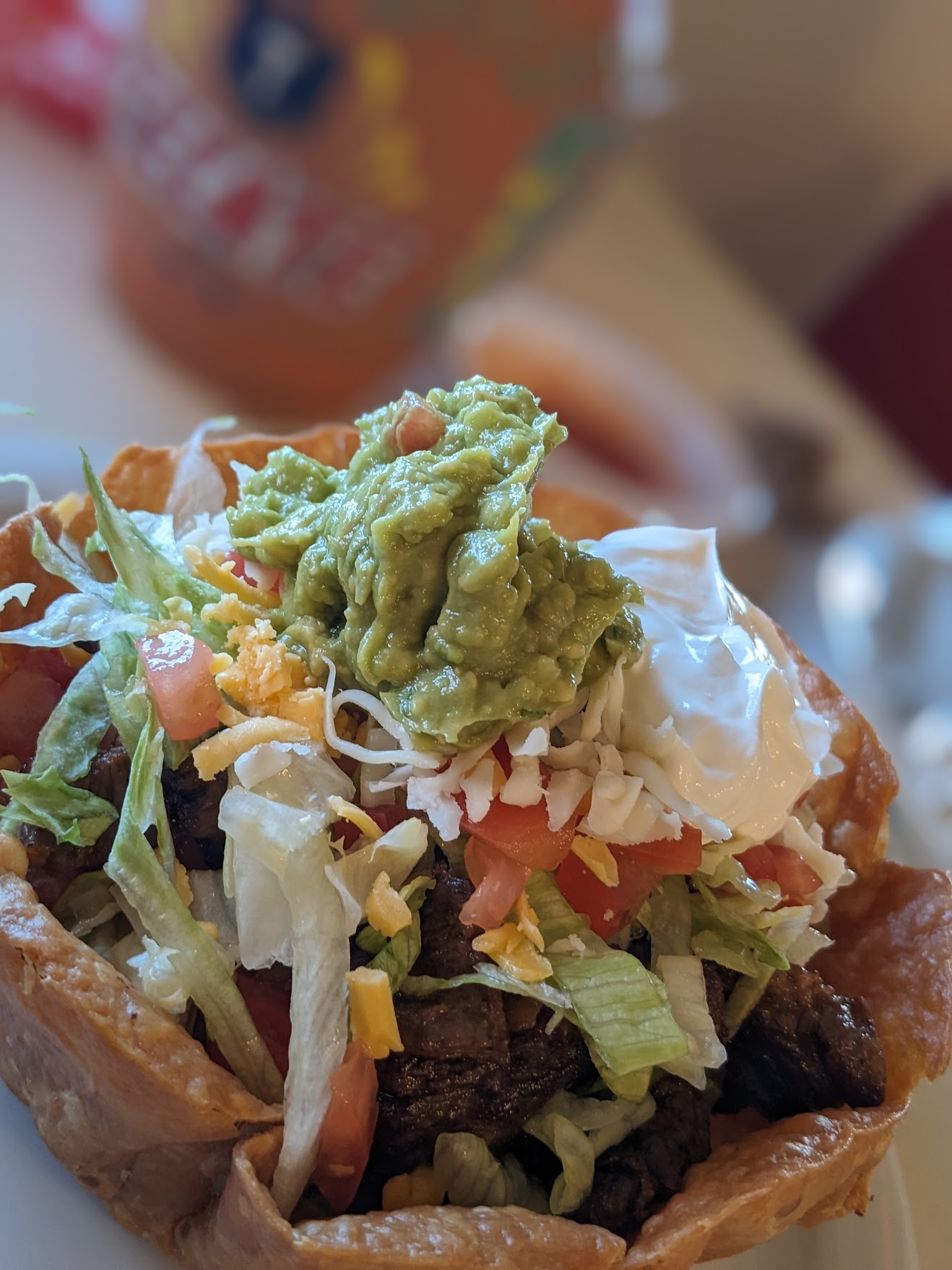 Crispy taco salad topped with guacamole and sour cream