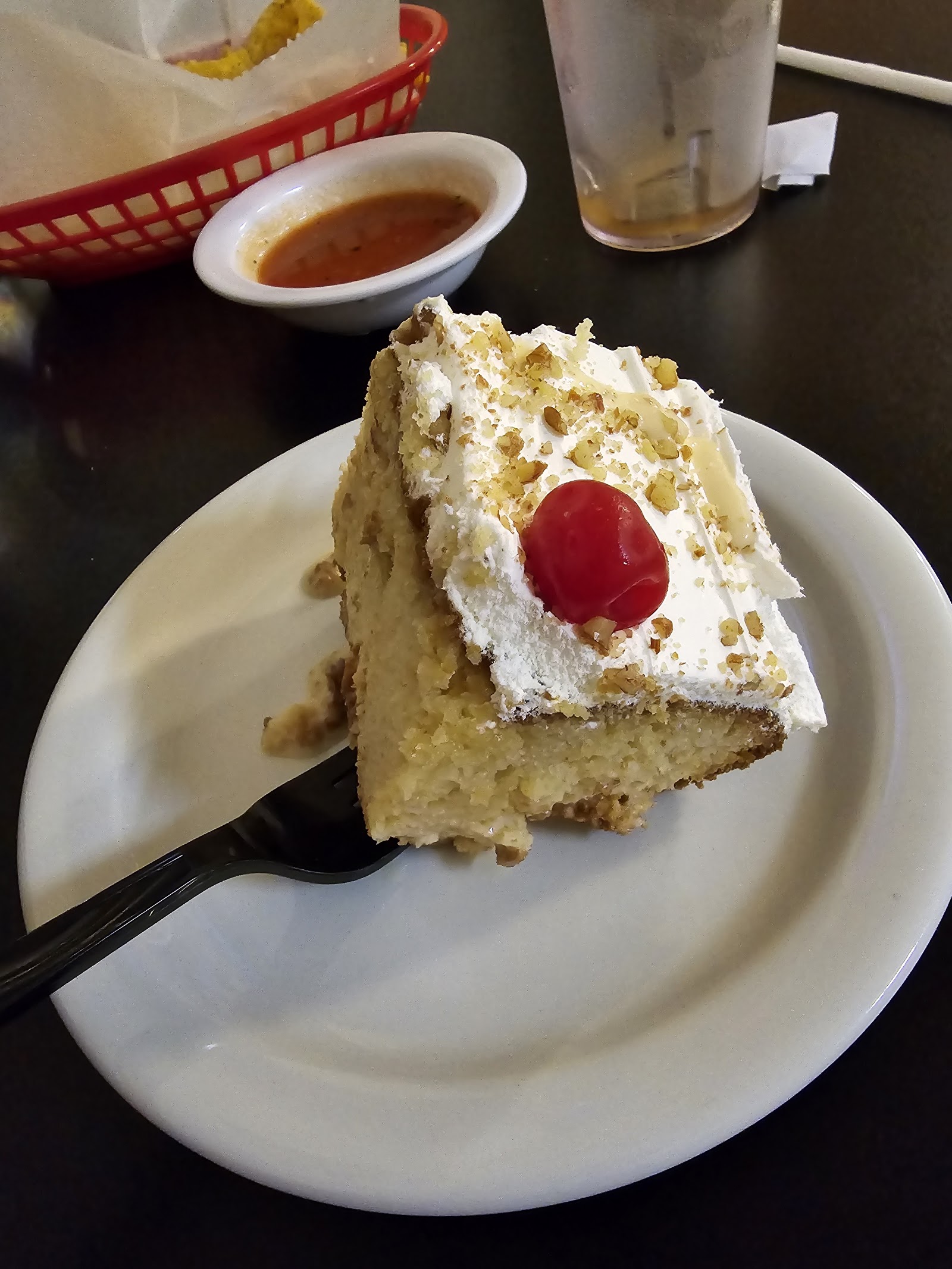 Slice of homemade tres leches cake topped with a cherry